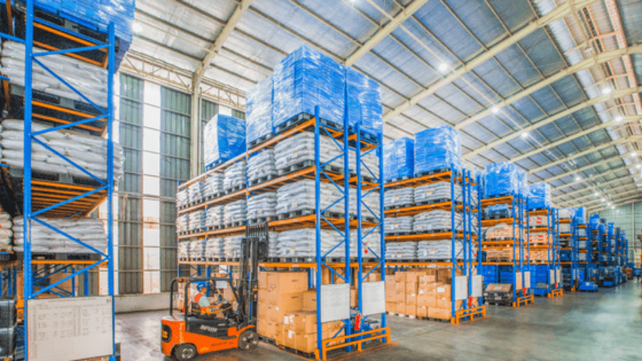 Warehouse with racks of pallets and a forklift in the foreground.