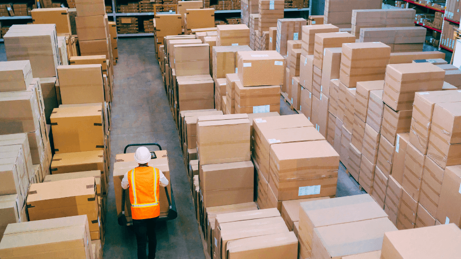 A worker trying to rearrange a warehouse that is too full with inventory.
