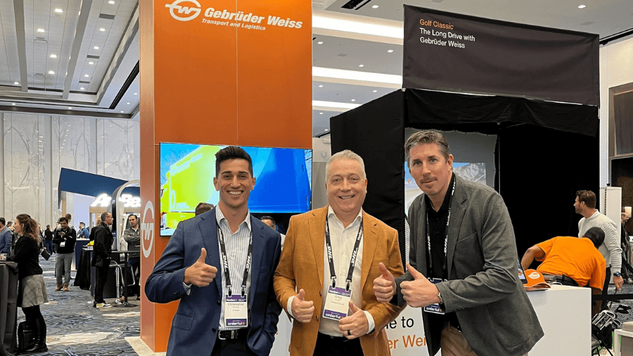 Networking at Manifest Vegas 2024. In the photo from left to right: Chris Perrone (uTenant), Greg Wuest (uTenant), and connection from Gebruder Weiss, all with double thumbs up, smiling at the camera.
