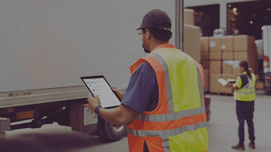 Two people in safety vest looking at warehouse relocation checklists, outside of their current warehouse.