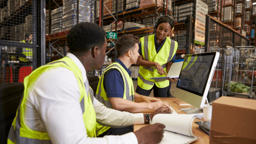 Three workers in 3PL warehouse discussing and order.