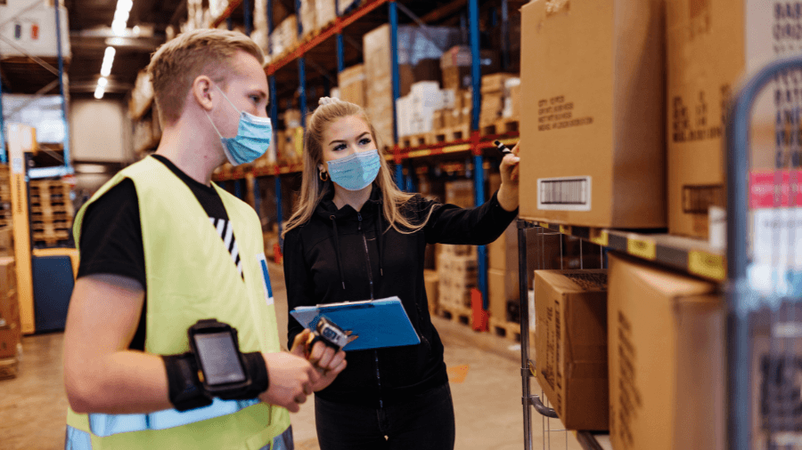 Two people working in a warehouse wearing PPE face masks