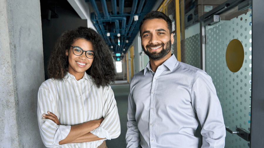 Two people smiling at the camera in an industrial facility setting