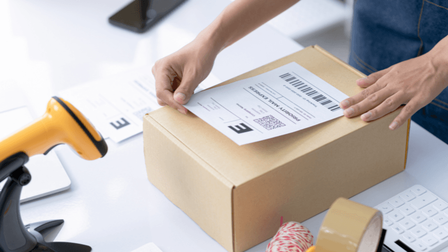 Someone applying a delivery label to an online order box.