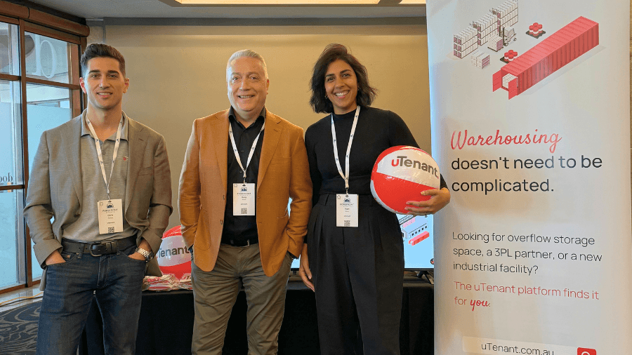 Chris Perrone, Greg Wuest, and Nam Atwal smiling at the camera, standing in front of the uTenant exhibition booth at The Supply Chain Summit NSW in June 2024