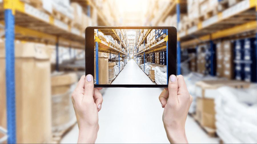 A photo showing a view down the aisle of a warehouse through a tablet camera on screen of a potential logistics solution.
